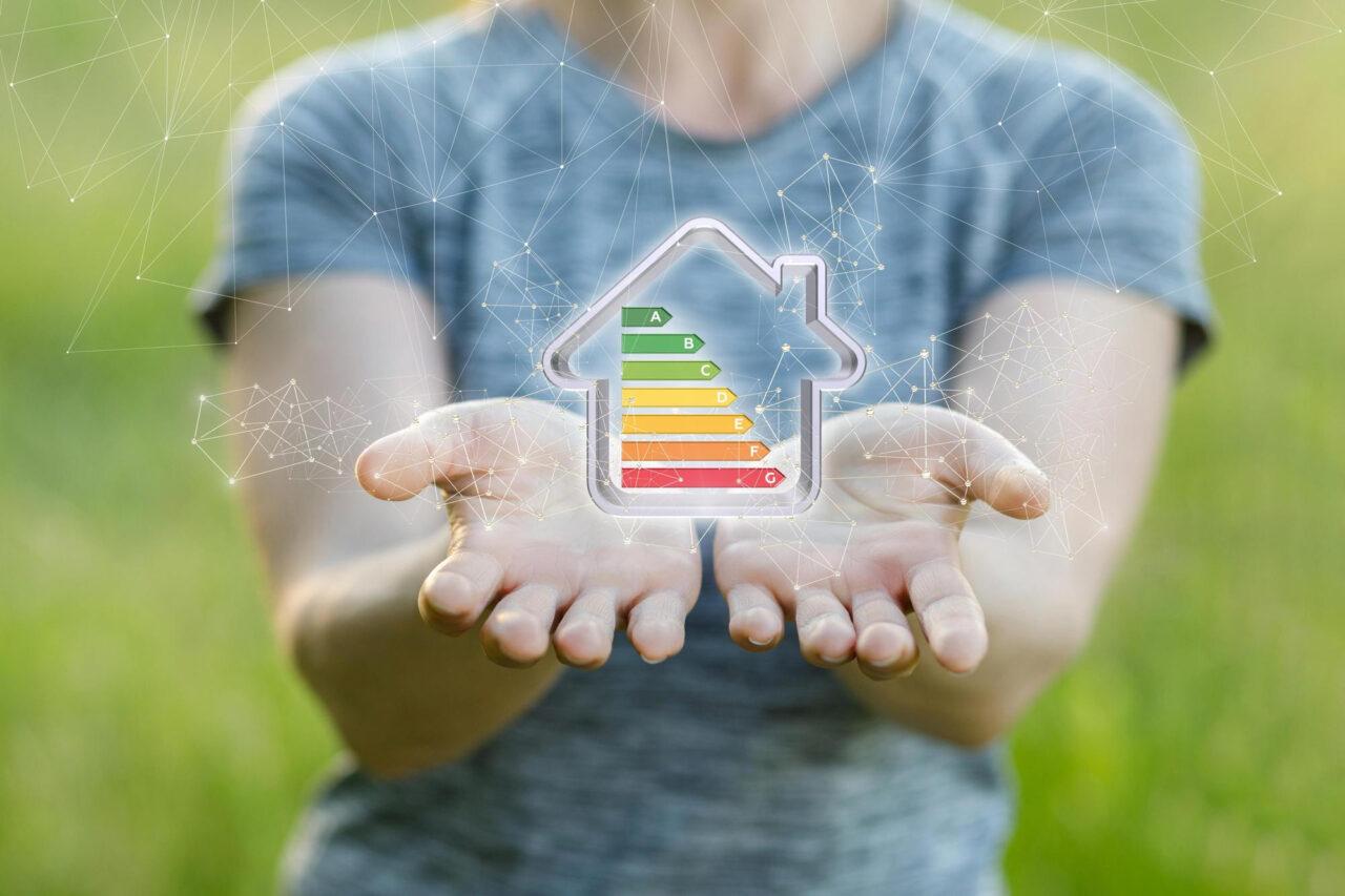Haus mit Energieeffizienzskala in den Händen einer Person.